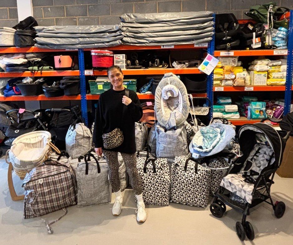 A volunteer surrounded by prams, Moses baskets and packed starter bundles