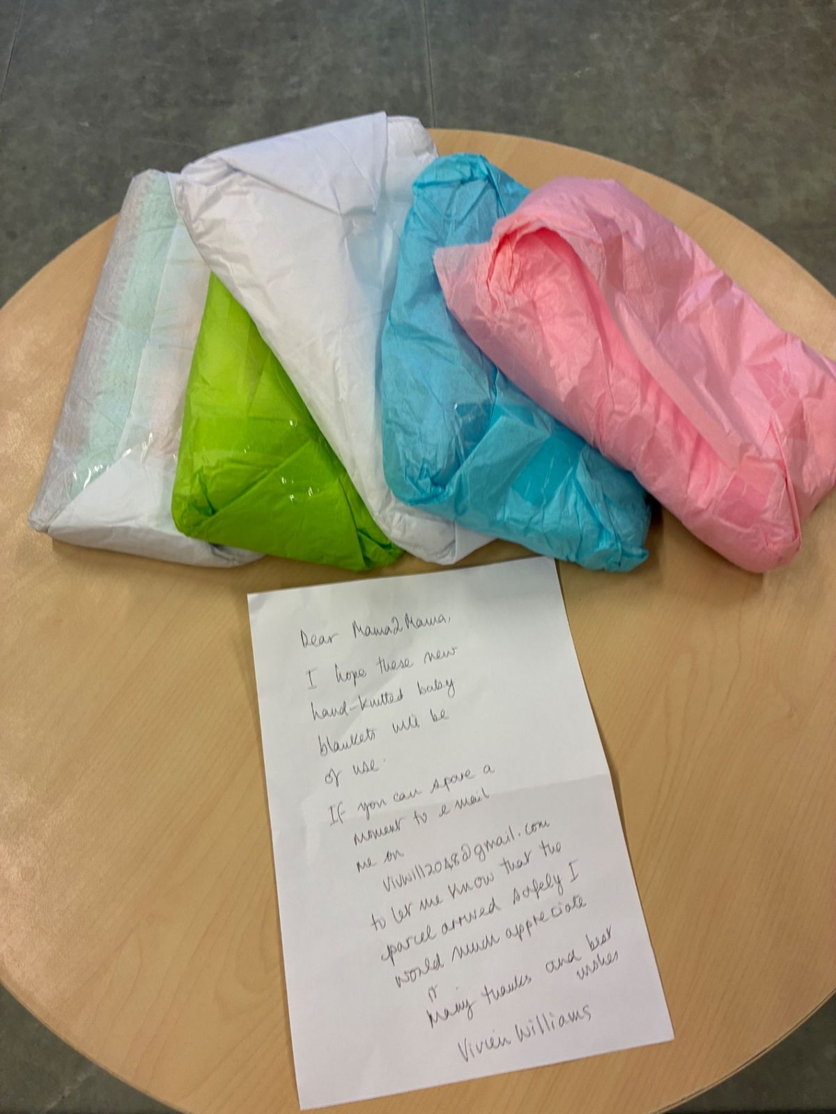 A handwritten thank-you letter beside folded baby clothes